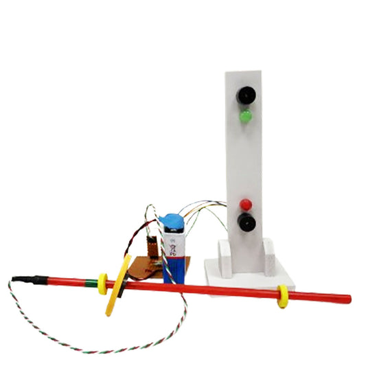 A homemade science project features a red rod with rings, connected to a small circuit board with a battery and wires—part of an inventive water level indicator. A vertical white stand with red and green buttons enhances the electronics kit setup.