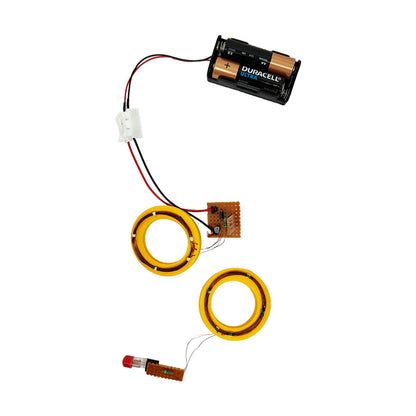 Explore the wonders of wireless power transfer with this science kit featuring a battery-powered circuit. It includes two yellow circular coils showcasing mutual inductance, a small circuit board, wires, and a distinctive red-tipped component.